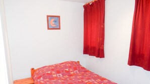 Una cama individual con colcha estampada, una mesita de noche de madera y un cuadro colgado en la pared.