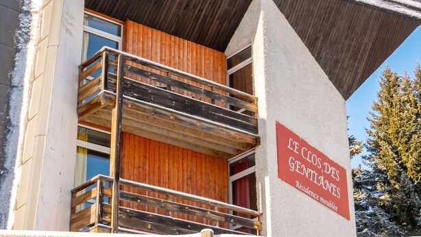 Un edificio con balcón de madera y un cartel que indica que es una residencia.