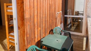 A room with a wooden wall, a green table, and a chair. - Homerez - Apartment in Allevard (Allevard)