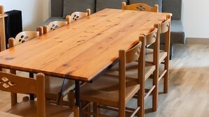 Una sala de conferencias con una larga mesa de madera y sillas, un sofá gris, y un mapa enmarcado en la pared.