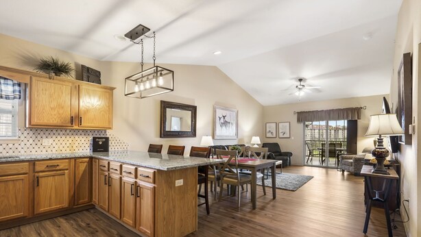 A spacious kitchen with wooden cabinets, a large island, and a dining area with chairs and a table. - 2 Bedroom, 2 Bathroom Golf Condo featuring Private, Covered Balcony with Pool View (Branson)