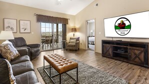 A living room with a sofa, armchair, ottoman, TV, and a ceiling fan. - 2 Bedroom, 2 Bathroom Golf Condo featuring Private, Covered Balcony with Pool View (Branson)