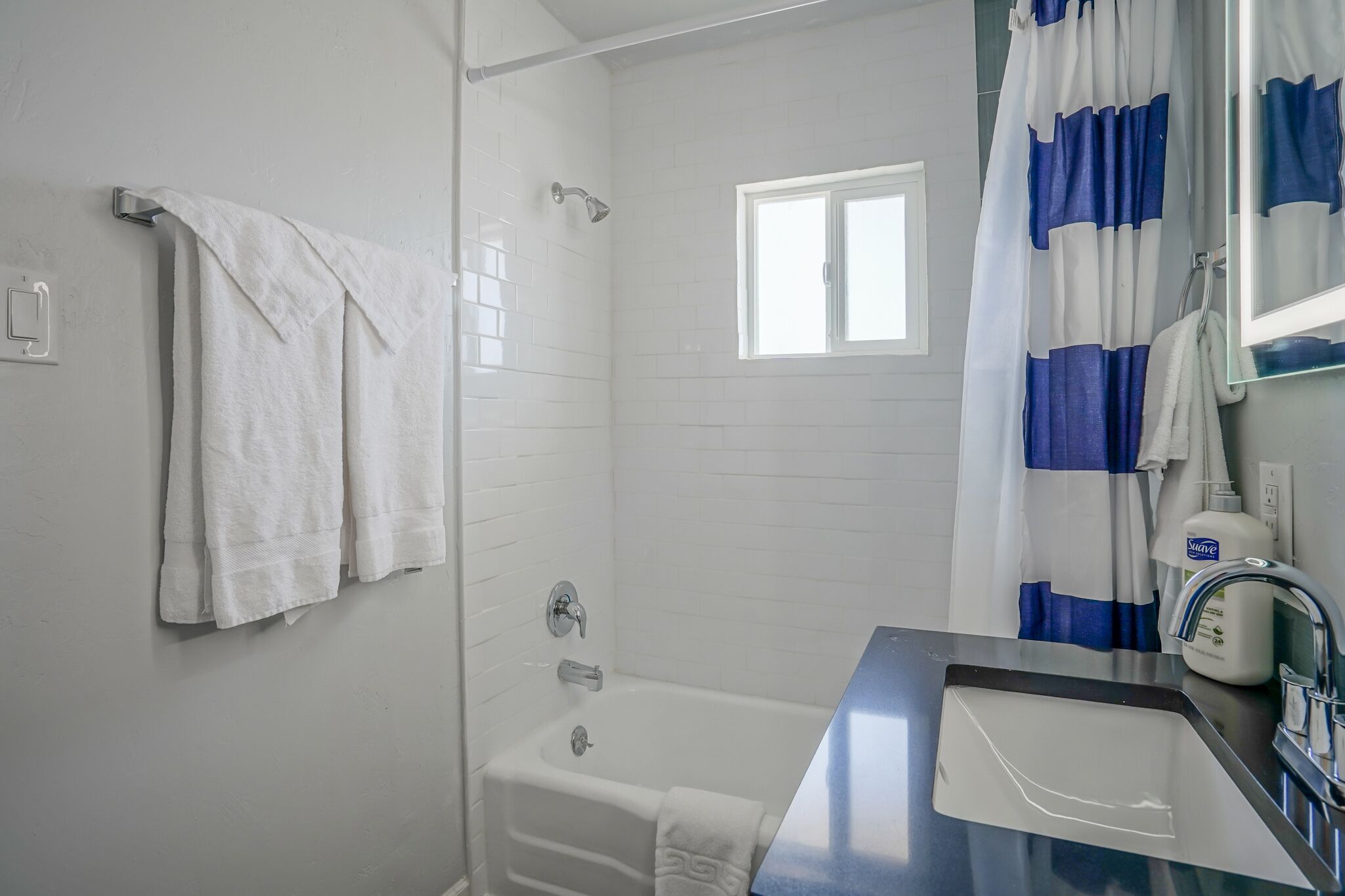 Un baño con bañera, ducha, ventana e lavabo con espejo.