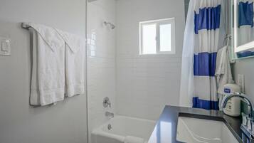 Un baño con bañera, ducha, ventana e lavabo con espejo.