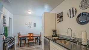 Eine moderne Küche mit Essbereich, Edelstahlgeräten und Wanddekoration.
