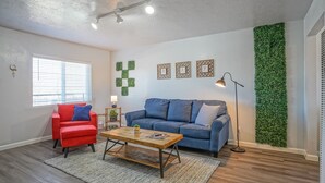 Ein Wohnzimmer mit einem blauen Sofa, einem roten Sessel und einem Holztisch.
