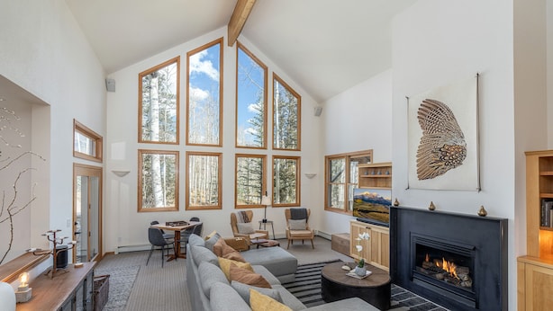 A spacious living room with a large fireplace, multiple windows, and a modern fireplace mantel. - HAVEN ON HANG GLIDER (Mountain Village)