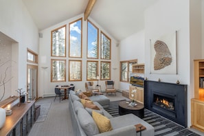 A spacious living room with a large fireplace, multiple windows, and a modern fireplace mantel.