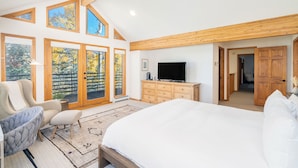 A bedroom with a large bed, a TV, wooden furniture, and a balcony with glass doors. - HAVEN ON HANG GLIDER (Mountain Village)