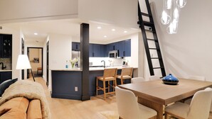 Una cucina moderna con mobili azzurri, un tavolo da pranzo in legno e una scala appoggiata al muro.