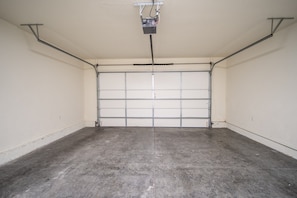 A garage with a concrete floor, a closed garage door, and overhead electrical wiring.