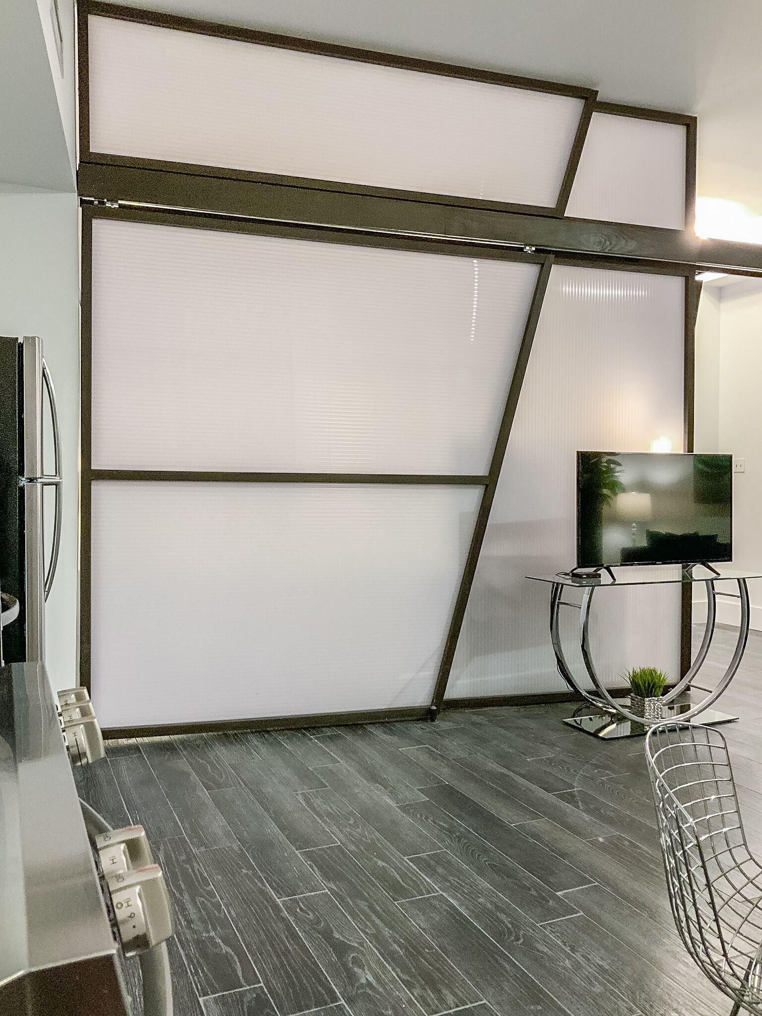 Un salon moderne avec un canapé d’angle, une table basse en verre et un téléviseur à écran plat.