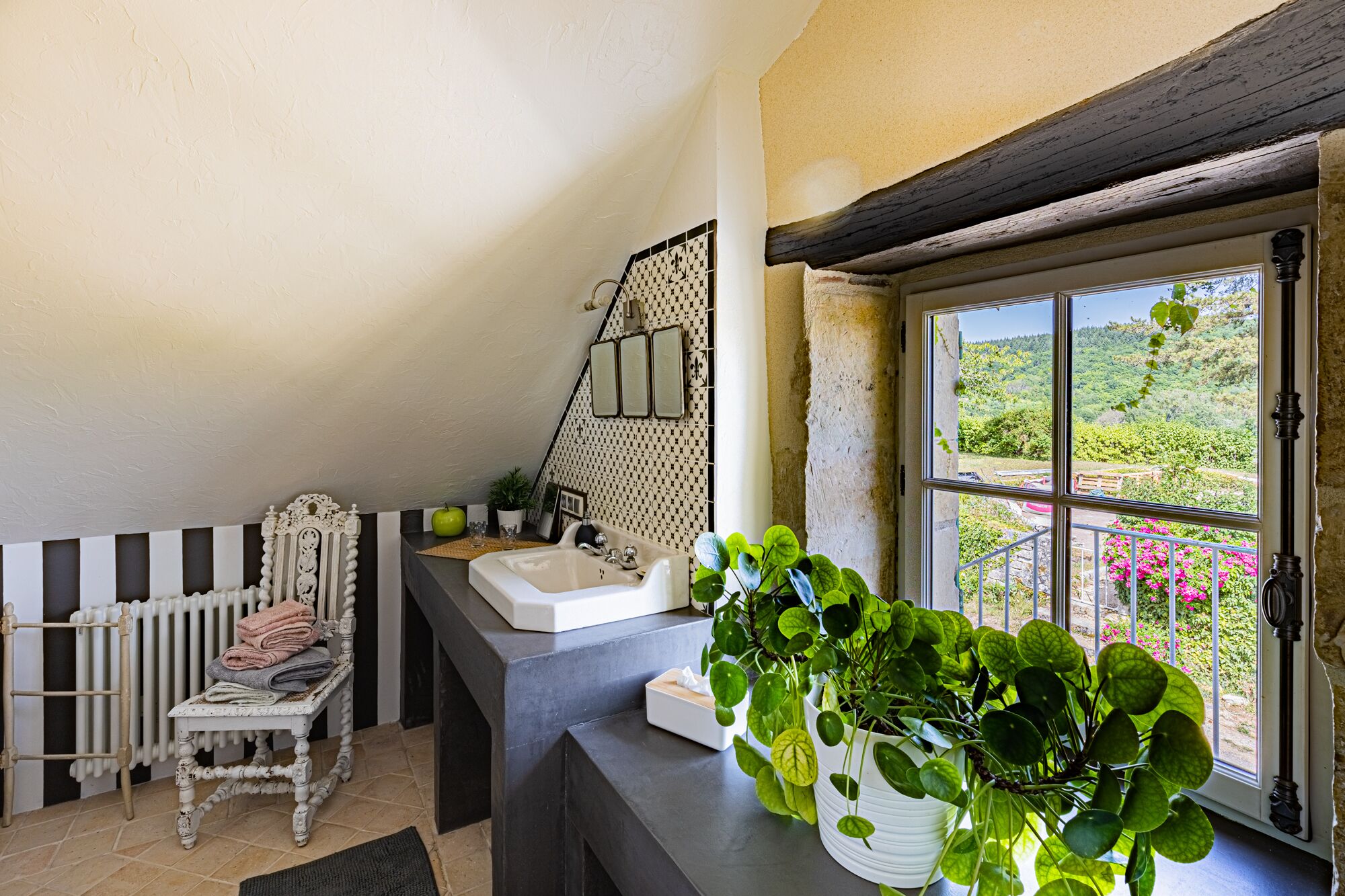 Casa de banho com lavatório, espelho e janela com vista para vegetação.