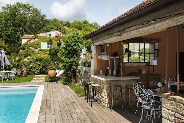 A poolside area with a bar, outdoor seating, and a view of the surrounding greenery. - Le Domaine des Carriers - Chambres (Chevroches)