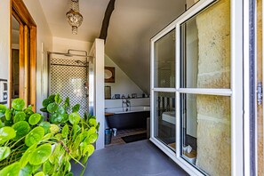 A bathroom with a bathtub, a shower, and a sink. There is a window and a plant in the foreground. - Le Domaine des Carriers - Chambres (Chevroches)