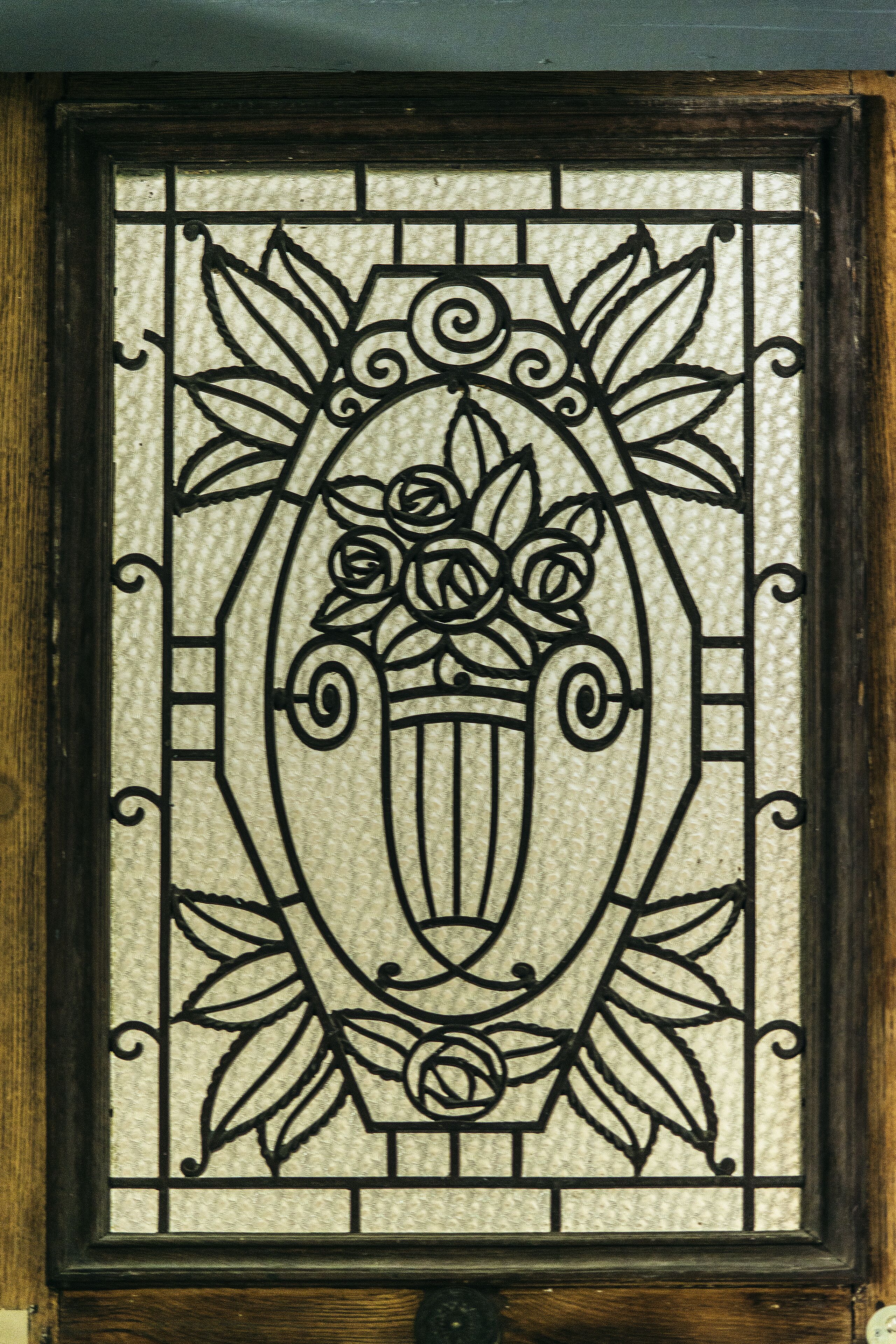 A decorative stained glass window with floral and scroll designs.