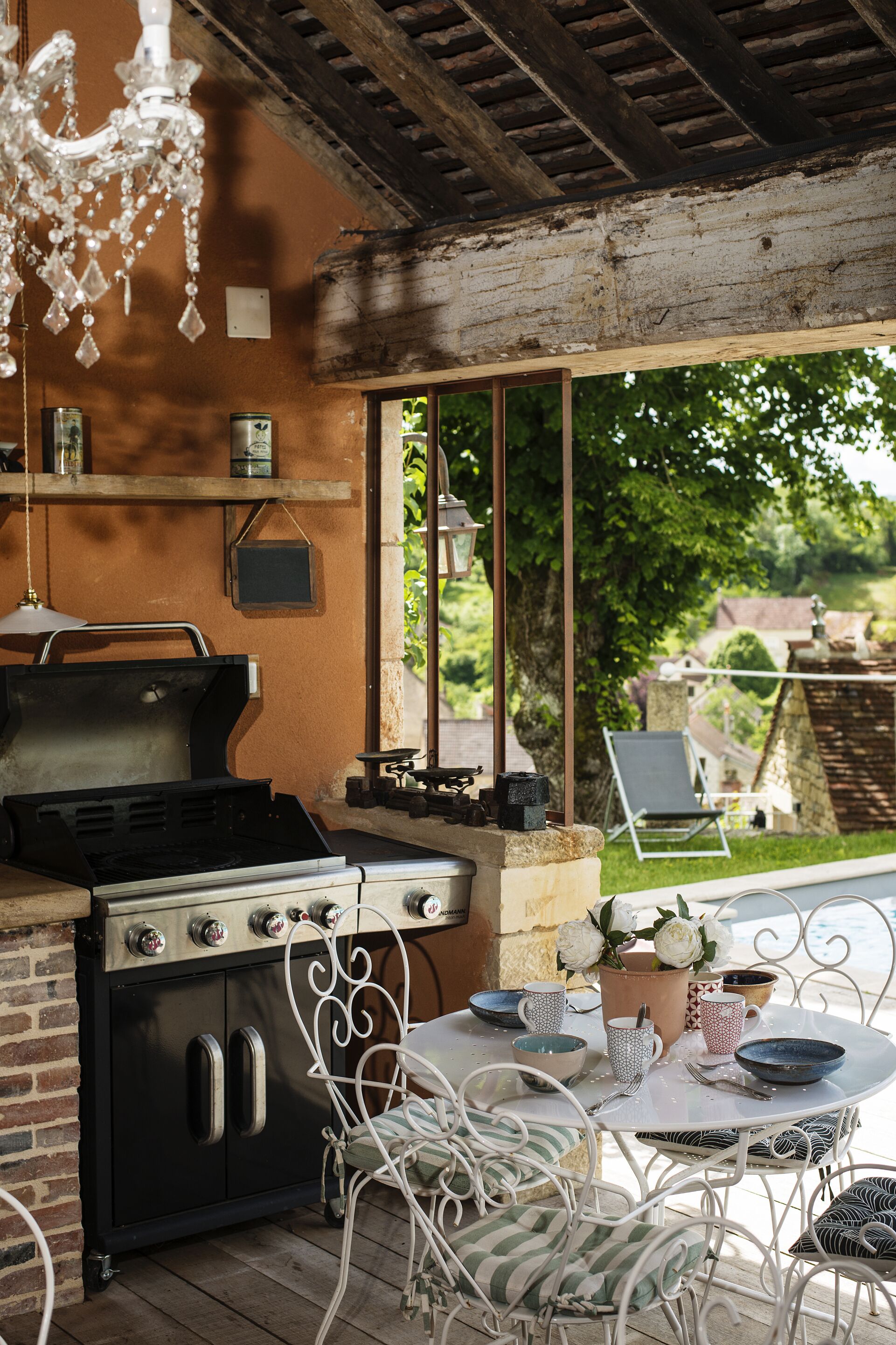 An outdoor kitchen area with a grill, dining table, and chairs.