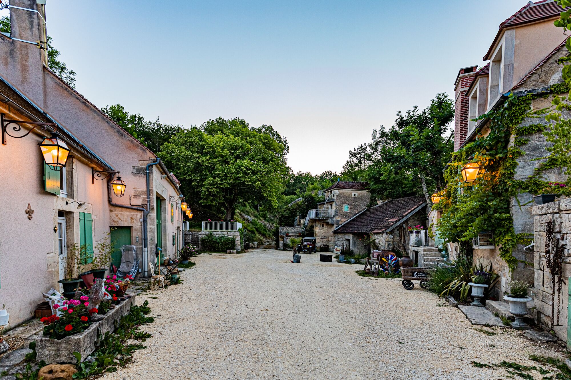 A cobblestone street lined with historic buildings, some with outdoor seating and potted plants.