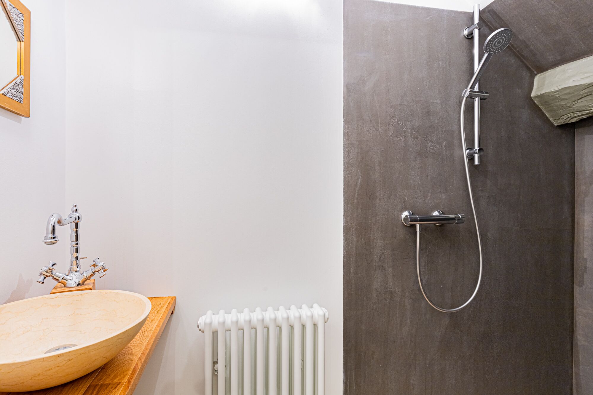 A bathroom with a wooden vanity, a white radiator, and a shower with a grey door.
