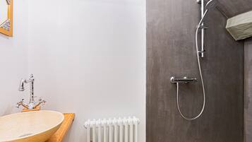 A bathroom with a wooden vanity, a white radiator, and a shower with a grey door.