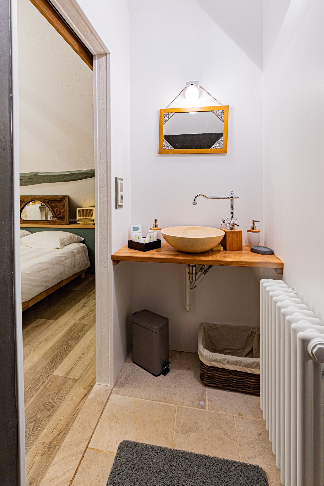 A compact bathroom with a wooden vanity, a large mirror, and a single sink.