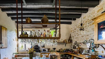 Una cocina rústica con vigas de madera a la vista, un estante colgante con botellas y diversos utensilios de cocina.