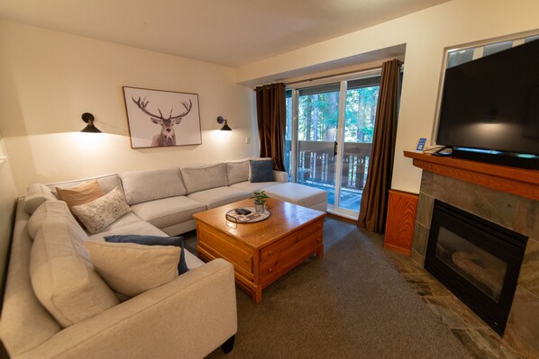 A living room with a sofa, a coffee table, a fireplace, and a television.