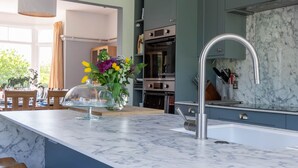 Una cocina moderna con encimera de mármol, pileta de acero inoxidable y taburetes de madera.