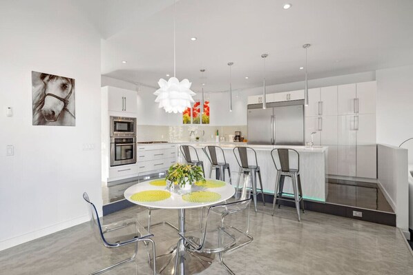 A modern kitchen with white cabinets, stainless steel appliances, and a central island with seating.