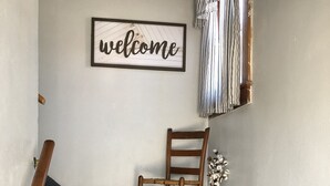 A staircase with a wooden chair and a welcome sign. - Carriage House on Main in NRG National Park  (Oak Hill)