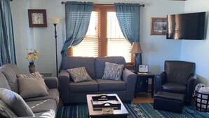 A living room with a sofa, armchair, coffee table, and a rug. - Papa Bear Cottage (Downtown Cody) (Cody)