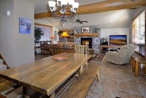 Una sala de estar acogedora con chimenea, una mesa de madera grande y asientos cómodos.