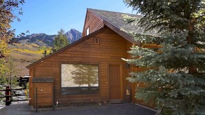 A wooden cabin with a large window, a door, and a small porch area. - Wildflower Villa (Crested Butte)