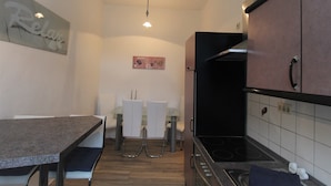 Una cocina compacta con una mesa de comedor, sillas, un refrigerador y una estufa.