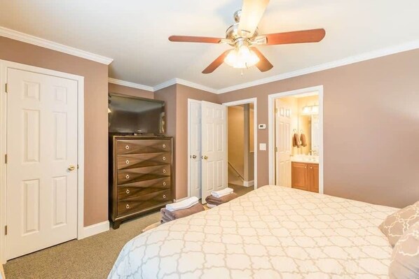 Ein Schlafzimmer mit Bett, Kommode, Kleiderschrank und Deckenventilator.