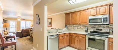 A kitchen with wooden cabinets, a stainless steel microwave, and an oven.