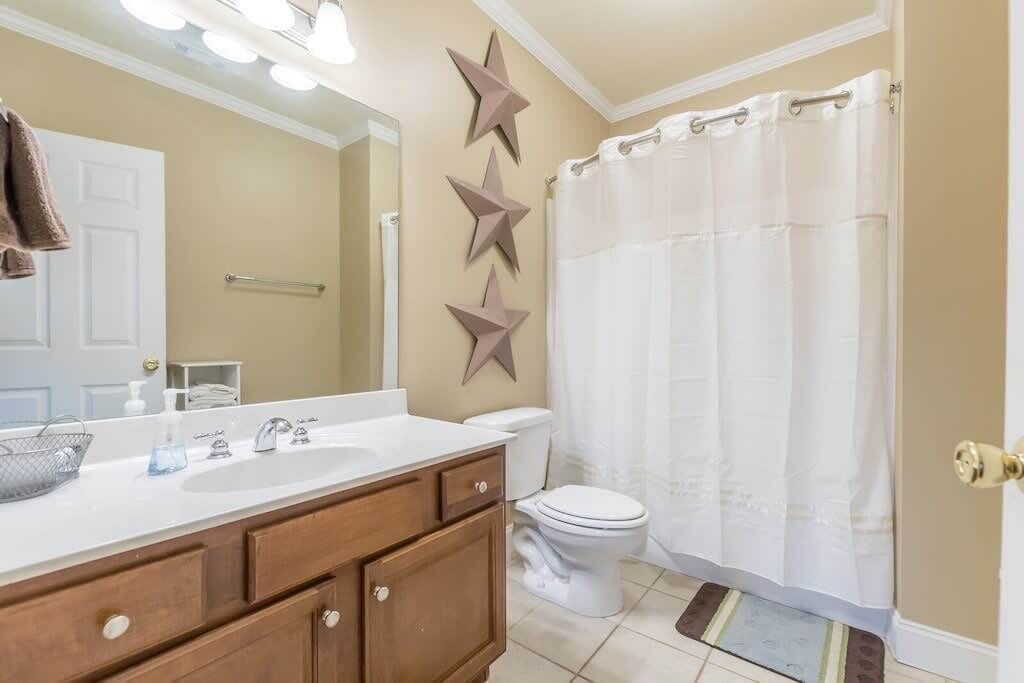 A bathroom with a white sink, wooden vanity, a toilet, and a shower curtain.