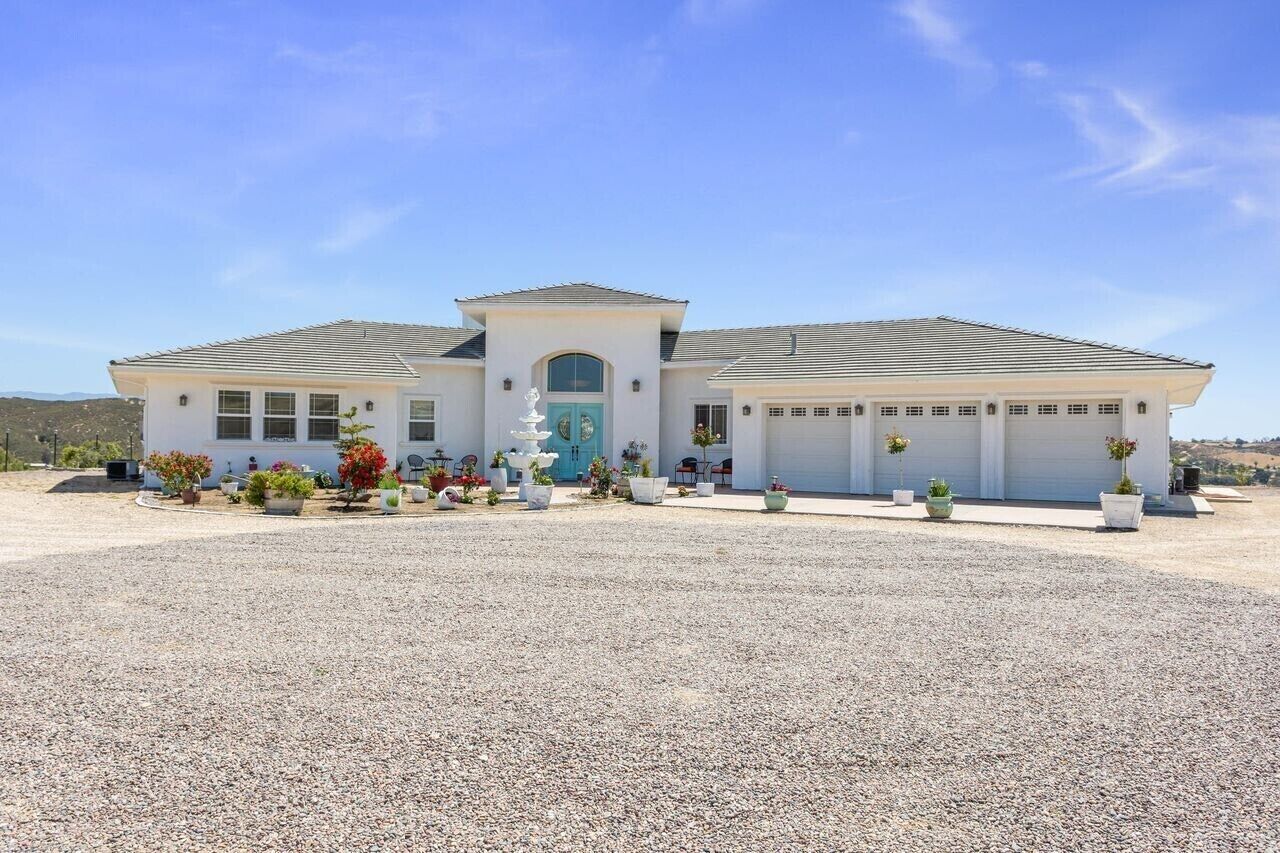 A two-story house with a central entrance, a garage, and a gravel driveway.