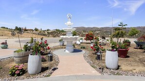 A garden with a central fountain, surrounded by potted plants and a clear view of the landscape. - Breathtaking view with a heated lap pool and pick ball court  (Temecula)
