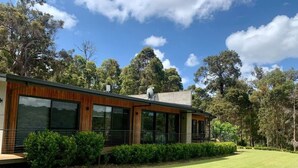 A modern house with large windows, a wooden exterior, and a well-maintained lawn.