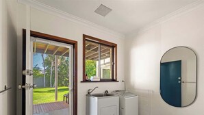 Een compacte keuken met een ingebouwde wasmachine en een spoelbak, een deur naar een balkon en een ronde spiegel aan de muur.