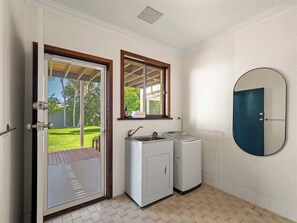 Een compacte keuken met een ingebouwde wasmachine en een spoelbak, een deur naar een balkon en een ronde spiegel aan de muur.