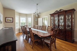 A dining room with a large wooden table, chairs, a chandelier, and a china cabinet. - Entire House:14 Guests, 7 BRs, 10 Beds, 5 Full Baths, Outdoor Shower, Beach Gear (Narragansett Pier)