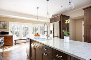 A modern kitchen with a large island, stainless steel appliances, and pendant lighting.