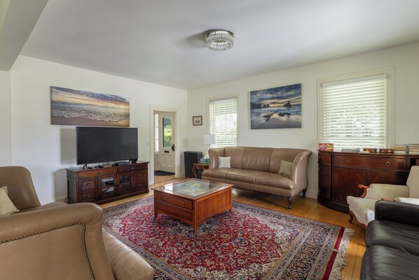 A living room with a television, leather sofas, a coffee table, and a large rug.