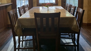 Comedor con una larga mesa, sillas de madera, una araña y amplias ventanas en arco.