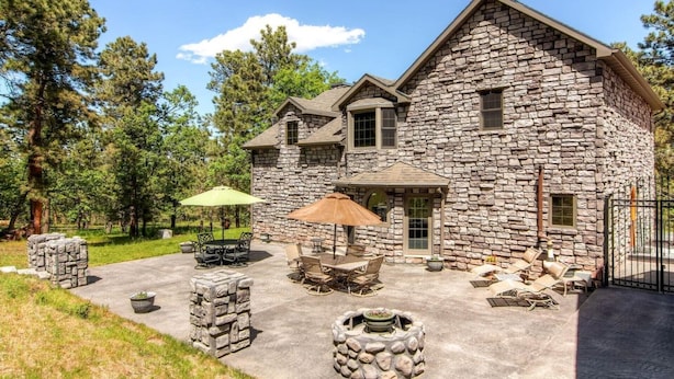 Una casa de piedra con un patio amoblado y una chimenea al aire libre.