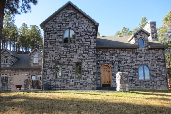 A stone building with a central entrance, multiple windows, and a sloped roof.