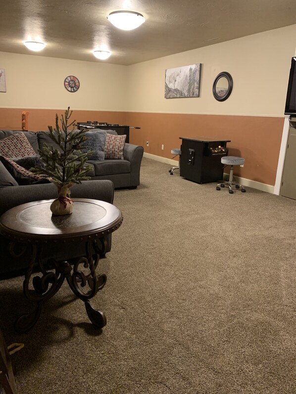 A living room with a gray sofa, a small round table with a decorative plant, a coffee table, and a cabinet with a stool.