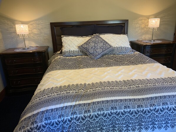 A neatly made bed with patterned bedding and two bedside lamps.